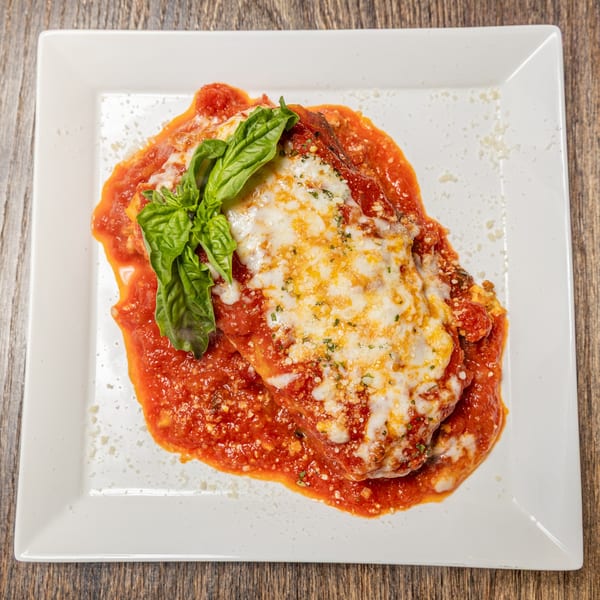 Celestino's Pizza & Pasta's lasagna, topped with melted cheese, rich red sauce, and fresh basil.